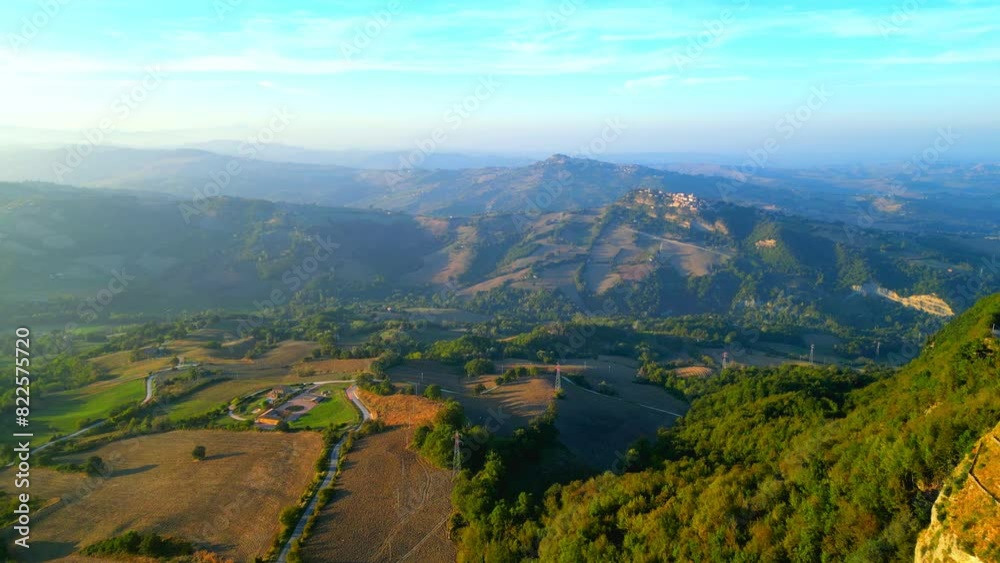 Wide aerial push-in shot from Smerillo (Fermo), from roads, utility poles, fields and thickets in the foreground to mountainous hillscapes with perched nearby villages and their vegetation in the back Wide aerial push-in shot from Smerillo (Fermo), from roads, utility poles, fields and thickets in the foreground to mountainous hillscapes with perched nearby villages and their vegetation in the back