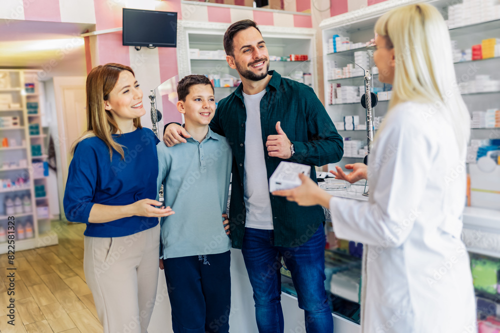Cheerful pharmacist chemist woman giving vitamins to young family of three in modern pharmacy. Cheerful pharmacist chemist woman giving vitamins to young family of three in modern pharmacy.
