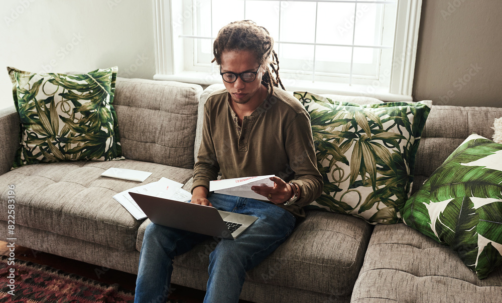 Documents, investment and laptop with black man on sofa in living room of home for bank or payment. Computer, finance and paper for budget with person in apartment for money, savings or tax audit Documents, investment and laptop with black man on sofa in living room of home for bank or payment. Computer, finance and paper for budget with person in apartment for money, savings or tax audit