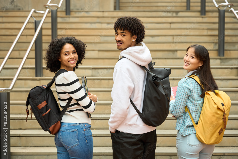 Fototapeta premium Three multiethnic students looking at camera with their backpacks