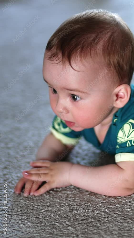 Little child banging his hands over the floor happily. Beautiful kid lies on a carpet looking up with interest. Vertical video Little child banging his hands over the floor happily. Beautiful kid lies on a carpet looking up with interest. Vertical video