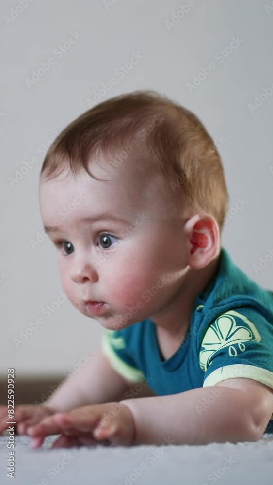Nice cute baby boy trying to crawl over the floor. Child looks straight ahead attentively trying to reach a toy. Vertical video Nice cute baby boy trying to crawl over the floor. Child looks straight ahead attentively trying to reach a toy. Vertical video