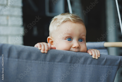 Baby boy swings in a swing at home. The child learns to have fun. Child development.
