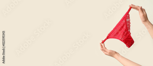 Female hands with stylish red panties on light background © Pixel-Shot