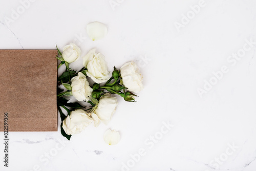 White garden roses in craft paper bag, floral greeting card, copy space