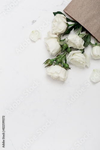 White garden roses in craft paper bag, floral greeting card, copy space