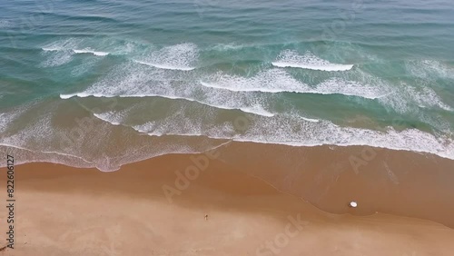 Praia quase vazia e surfistas no mar azul no litoral do nordeste brasileiro. Drone filmando de cima surfistas pequenos na amplitude do mar em Taipu de Fora, Bahia, Brasil photo