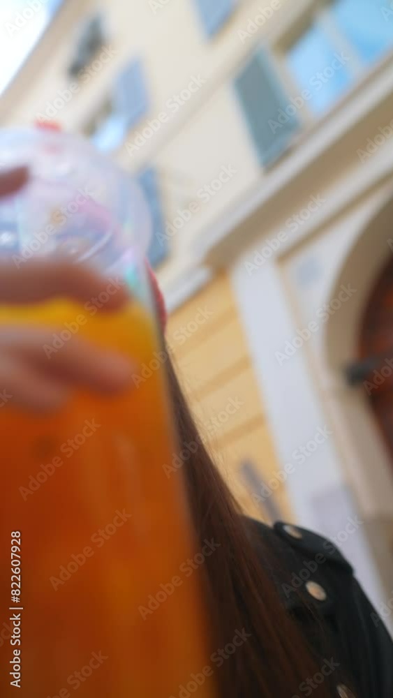 A trendy girl strolls through an Italian city, savoring a cool beverage. A trendy girl strolls through an Italian city, savoring a cool beverage.