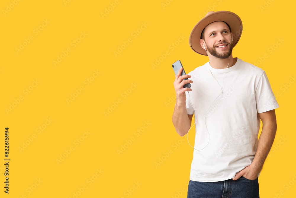 Happy young man in modern earphones with mobile phone on yellow background Happy young man in modern earphones with mobile phone on yellow background