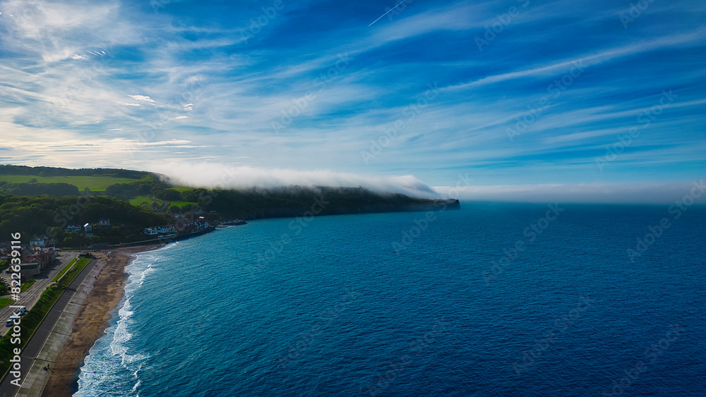 Fototapeta premium Aerial view of coastal landscape with beach and foggy headland in Sandsend, Yorkshire