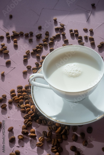 cup of milk and coffee beans on pink background