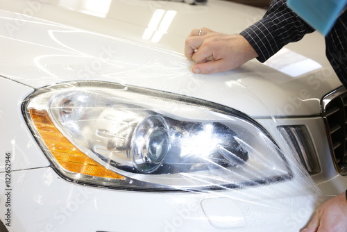 The process of installing PPF film on the headlight of the car. Selective, blurred focus. The concept of car body protection. Wrapping car. 