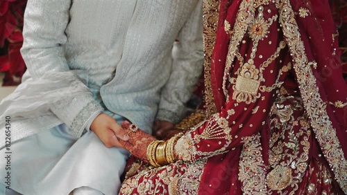 Groom tying cultural sacred thread on brides hand at a traditional Indian wedding. Indian wedding ritual
