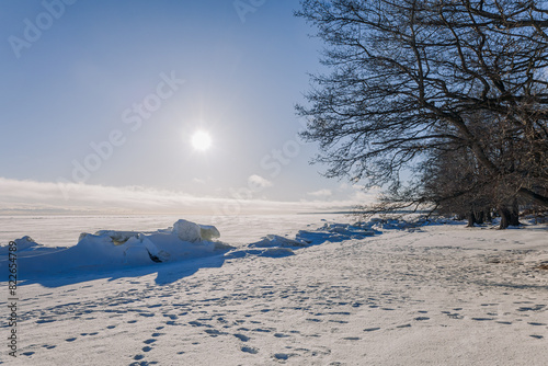 Winter landscape. Panoramic view of beautiful sunset on bay. Ice, snow and rocks on coastline. Setting sun in bright light. High quality photo © lara-sh