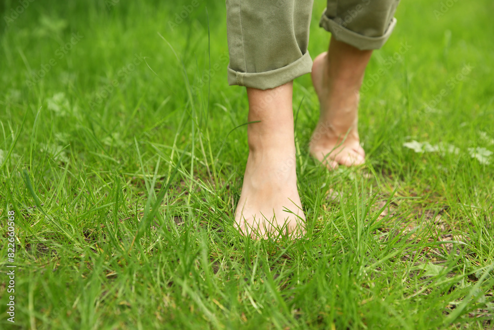 Woman walking barefoot on green grass outdoors, closeup Woman walking barefoot on green grass outdoors, closeup