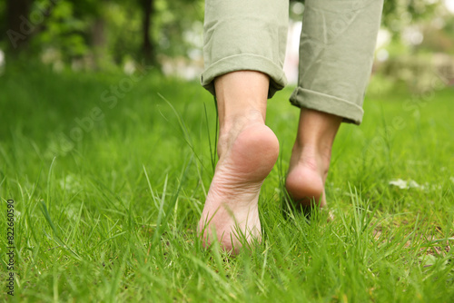 Woman walking barefoot on green grass outdoors, closeup