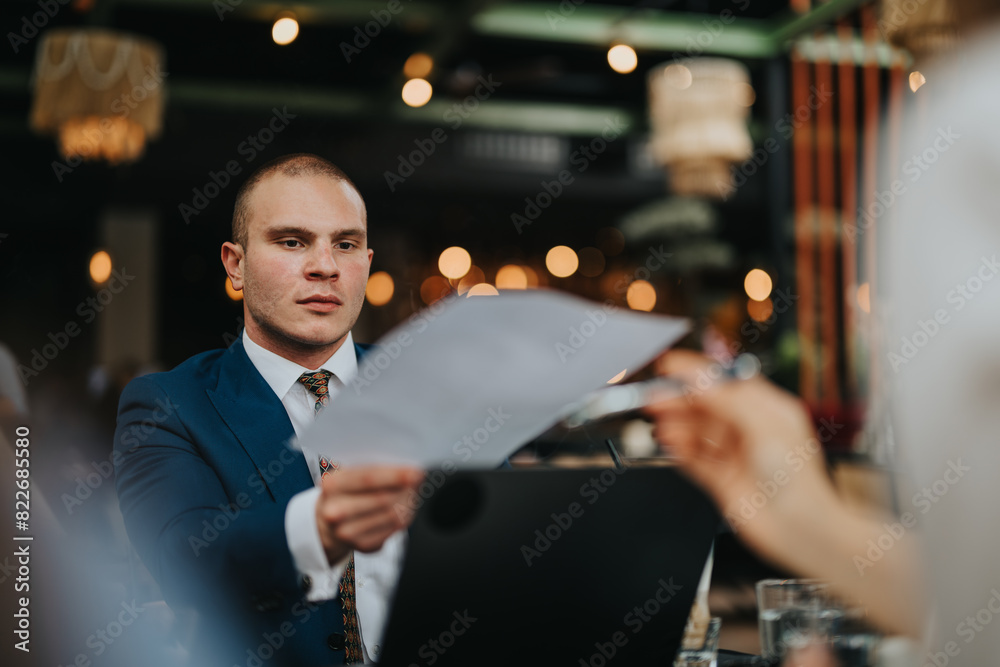 Businessman in formal suit analyzing documents during a meeting in a modern coffee bar setting with bokeh lights in the background.