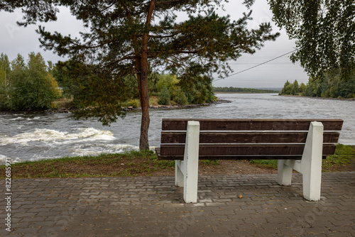 In the park, on the high bank of the river, there is a bench between the pines for a secluded rest.