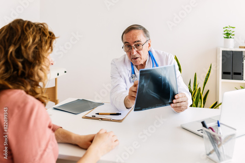 Mature doctor having discussing with female patient over medical x-ray at hospital