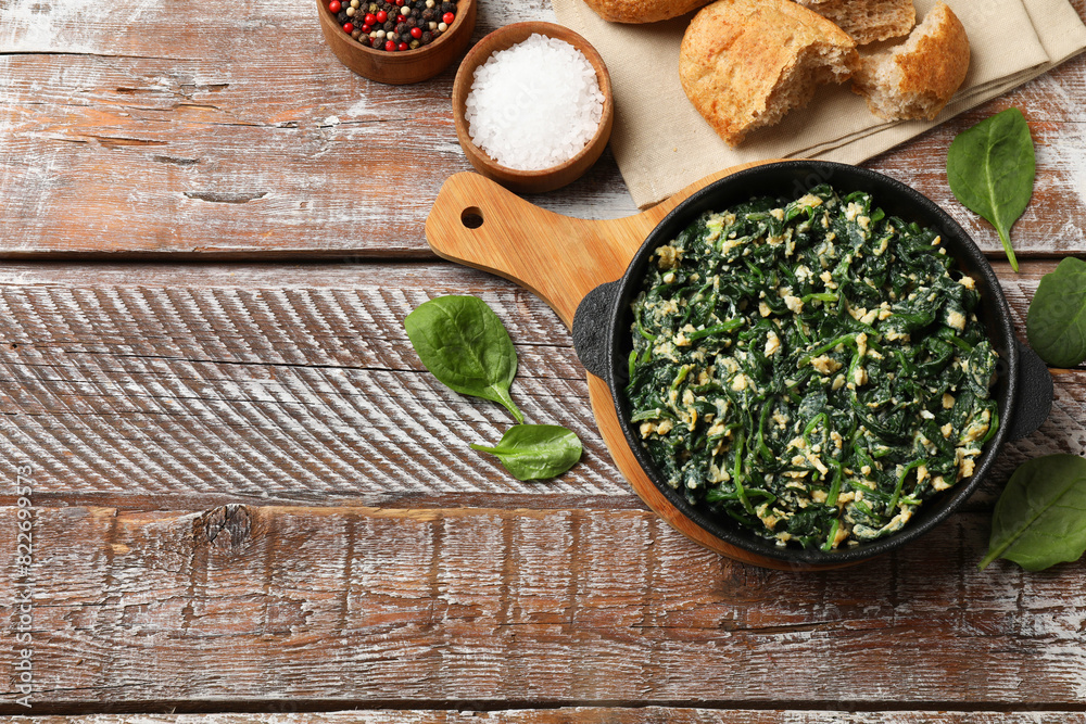 Tasty spinach dip with eggs in dish served on wooden table, flat lay. Space for text Tasty spinach dip with eggs in dish served on wooden table, flat lay. Space for text