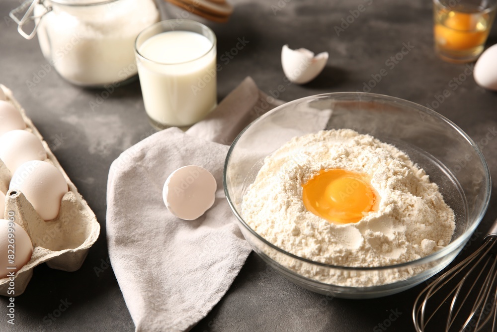 Making dough. Flour with egg yolk in bowl on grey textured table, closeup Making dough. Flour with egg yolk in bowl on grey textured table, closeup