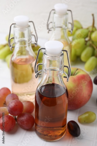 Different types of vinegar and ingredients on light tiled table, closeup