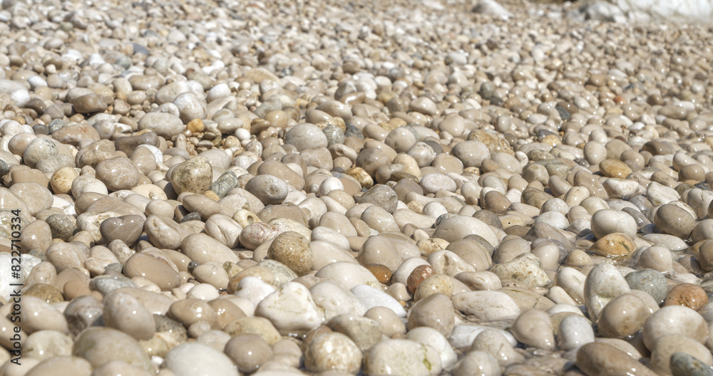 CLOSE UP: Sunny seashore with wet white pebbles on an beautiful island of Hvar. Stunning texture of small round stones scattered along the coast of Dalmatia glisten after being wetted by the sea. CLOSE UP: Sunny seashore with wet white pebbles on an beautiful island of Hvar. Stunning texture of small round stones scattered along the coast of Dalmatia glisten after being wetted by the sea.