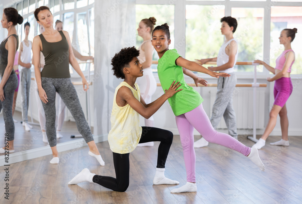 Fototapeta premium Thin teenage boy and girl doing together arabesque position of ballet during choreography classes