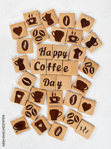 LIttle coffee square cookies with a filling of coffee marmalade in the form of a picture of a cup, a heart, a coffee pot, beans, words of a happy coffee day, love. Top view
