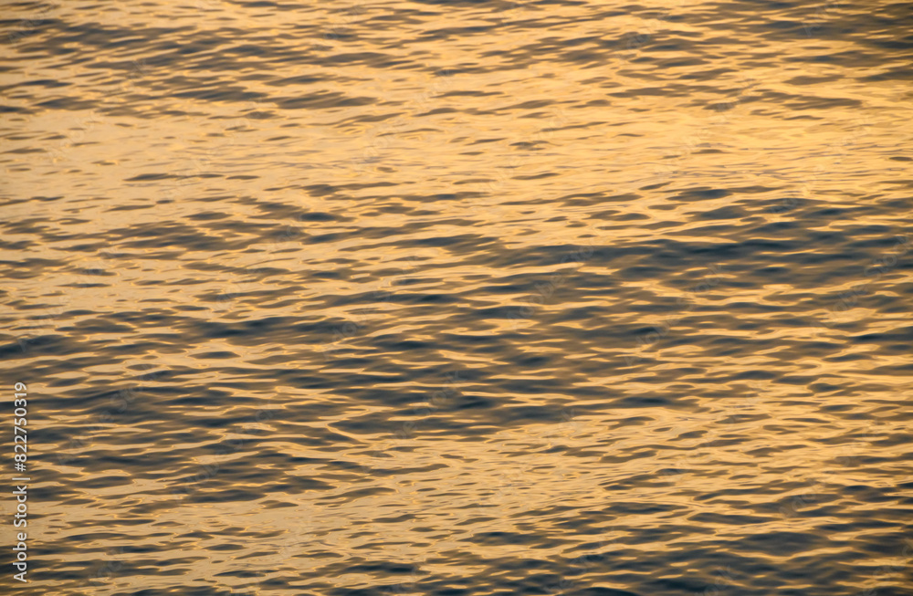 Mediterranean sea waves of golden color at sunset. water background Mediterranean sea waves of golden color at sunset. water background
