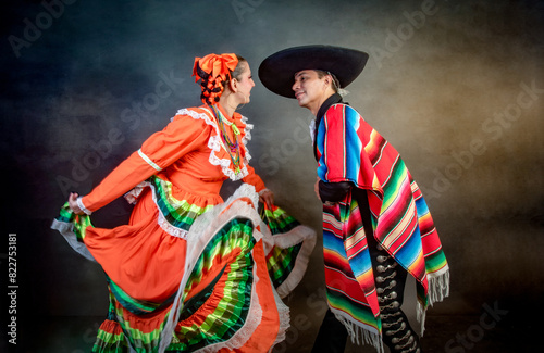 Latin Mexican couple with Jalisco, charro costumes A man and woman in traditional Mexican clothing dance together