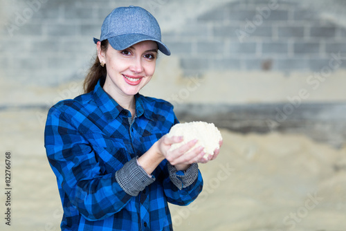 Woman farmer checks the quality of cornmeal in an animal feed warehouse photo