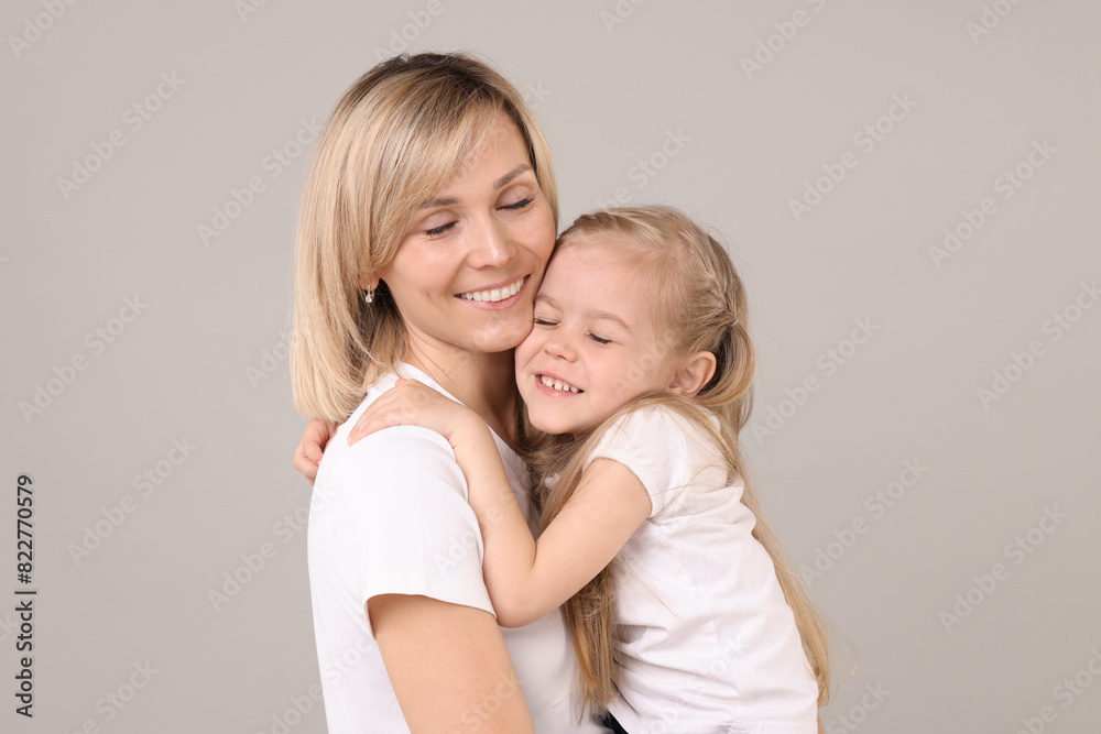 Family portrait of happy mother and daughter on grey background Family portrait of happy mother and daughter on grey background