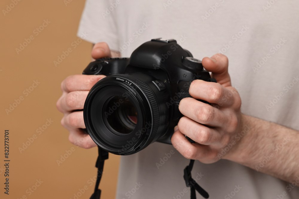 Photographer holding camera on beige background, closeup Photographer holding camera on beige background, closeup