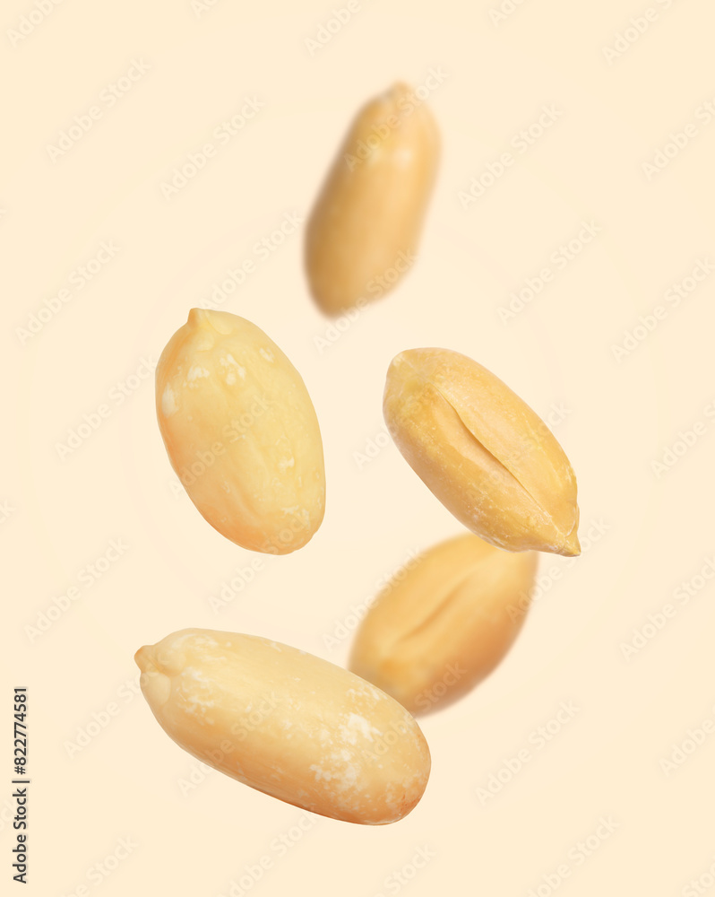 Many peanuts in air on beige background Many peanuts in air on beige background
