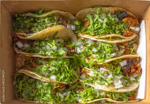 A horizontal view of Mexican Carnitas tacos garnish with cilantro and white onion.