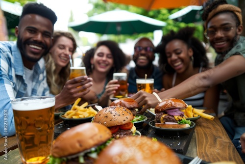 A diverse group of friends dine at an outdoor cafe  enjoying burgers and drinking beer together.