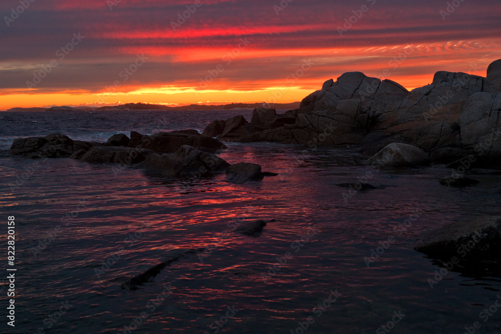 Naklejka premium Colourful Sunset Over Rocky Silhouette Ocean