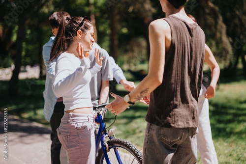 A joyful group of three friends discuss and prepare for a bike ride in a lush park on a sunny weekend, sharing laughs and good vibes. © qunica.com