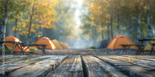 A camping site with tents and chairs is blurred in the background, with a wooden tabletop in the foreground for product display.