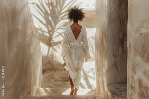 Serene Morning: Woman in White Robe Ascending Stairs With Self-Care Kit in Natural-Lit Minimalistic Interior photo