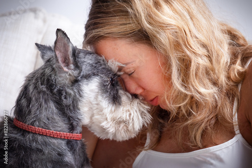 Girl and a schnauzer dog leaning their foreheads