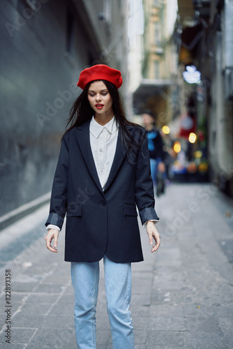 Fashion woman portrait walk tourist in stylish clothes with red lips and red beret walking down a narrow city street, travel, cinematic color, retro vintage style.