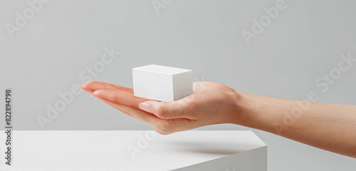 Crisp, clean frost white angular cream mockup presented by a woman in an extended view. photo