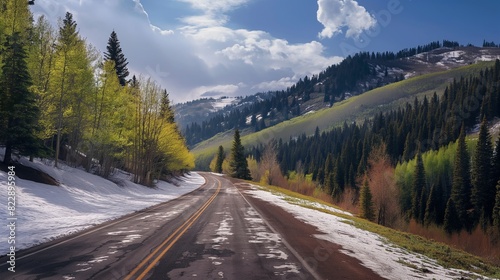 A mountain road during early spring, with patches of snow still visible and budding green trees lining the road. 32k, full ultra hd, high resolution