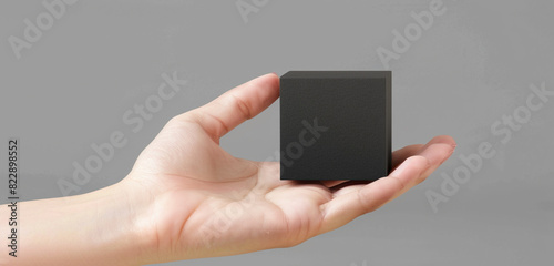 Feminine hand with a sleek and modern charcoal black minimalist cube cream mockup, panoramic view. photo