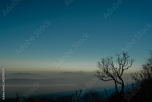 A photo of a view of mountains with clouds and clear blue sky seen from the top of Mount Ciremai, West Java, Indonesia photo