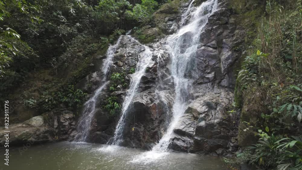 Peaceful Marinka waterfall cascading down rocky cliffs into a tranquil pool in a lush green forest setting, Minca Peaceful Marinka waterfall cascading down rocky cliffs into a tranquil pool in a lush green forest setting, Minca