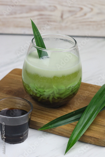 Cendol Pandan, one of popular Indonesian traditional drink, made from rice flour, pandan leaves extract, coconut milk and liquid of palm sugar. White marble background with copy space.