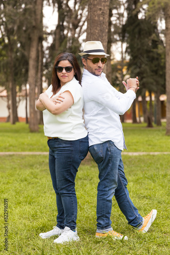 A man and a woman are posing for a picture in a park